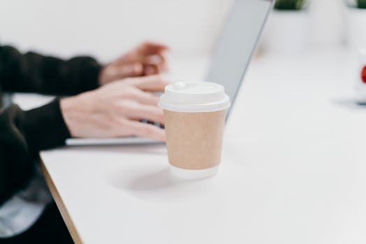 A minimalist home office setup with a laptop and coffee, ideal for remote work.