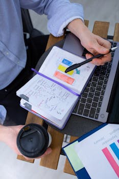 Man working with notes and laptop over a coffee break, analyzing charts.