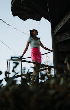 Young woman in pink skirt on a staircase, a balance of industrial and natural elements.