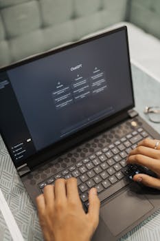 Close-up of hands typing on a laptop with AI software on the screen, highlighting modern technology use.